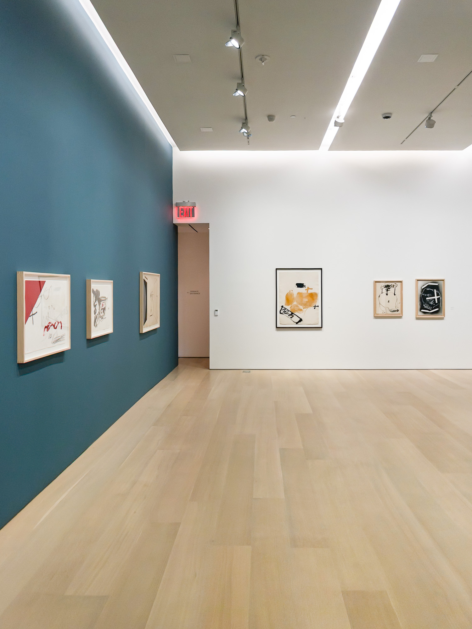 Museum gallery with teal accent wall and framed works